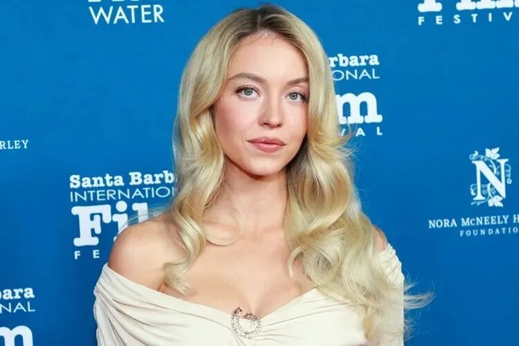 Сидни Суини в белом платье на фоне фестиваля