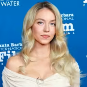 Сидни Суини в белом платье на фоне фестиваля