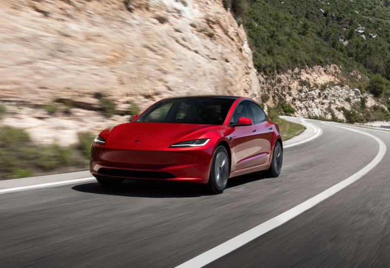 красный Tesla Model 3 на горной дороге