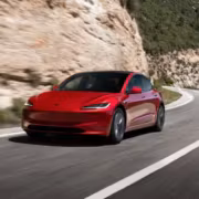 красный Tesla Model 3 на горной дороге
