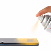 Человек наносит спрей на мобильный телефон iFixit T1 Phone