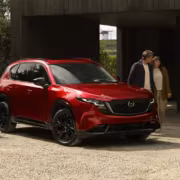Красный кроссовер Mazda рядом с двумя женщинами и мужчиной
