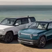 Два электромобиля Rivian R1T и R1S на берегу моря
