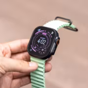 Рука держит умные часы Apple Watch Ultra со светло-зеленым ремешком