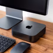 Компьютер Apple Mac mini на столе рядом с клавиатурой и мышью