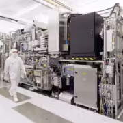 Человек в чистой одежде у крупного технологического оборудования ASML