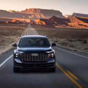 Черная Audi Q9 на пустой дороге у красных скальных формаций