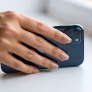 Человек держит смартфон Apple iPhone 12 с тройной камерой