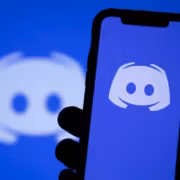 Смартфон с логотипом Discord в руке, фоновое изображение логотип Discord