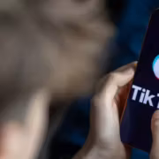 Еврокомиссия обвинила TikTok в слабой защите аккаунтов несовершеннолетних 1 Человек держит смартфон с логотипом TikTok
