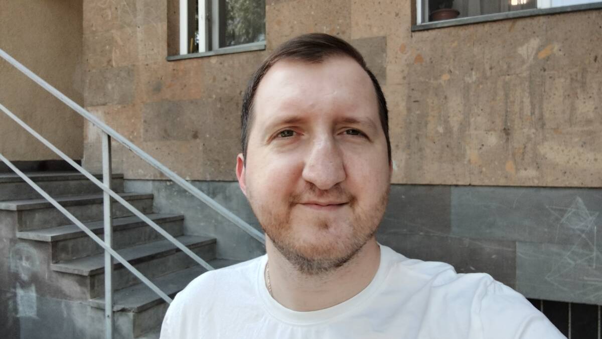 Мужчина в белой футболке на улице возле здания