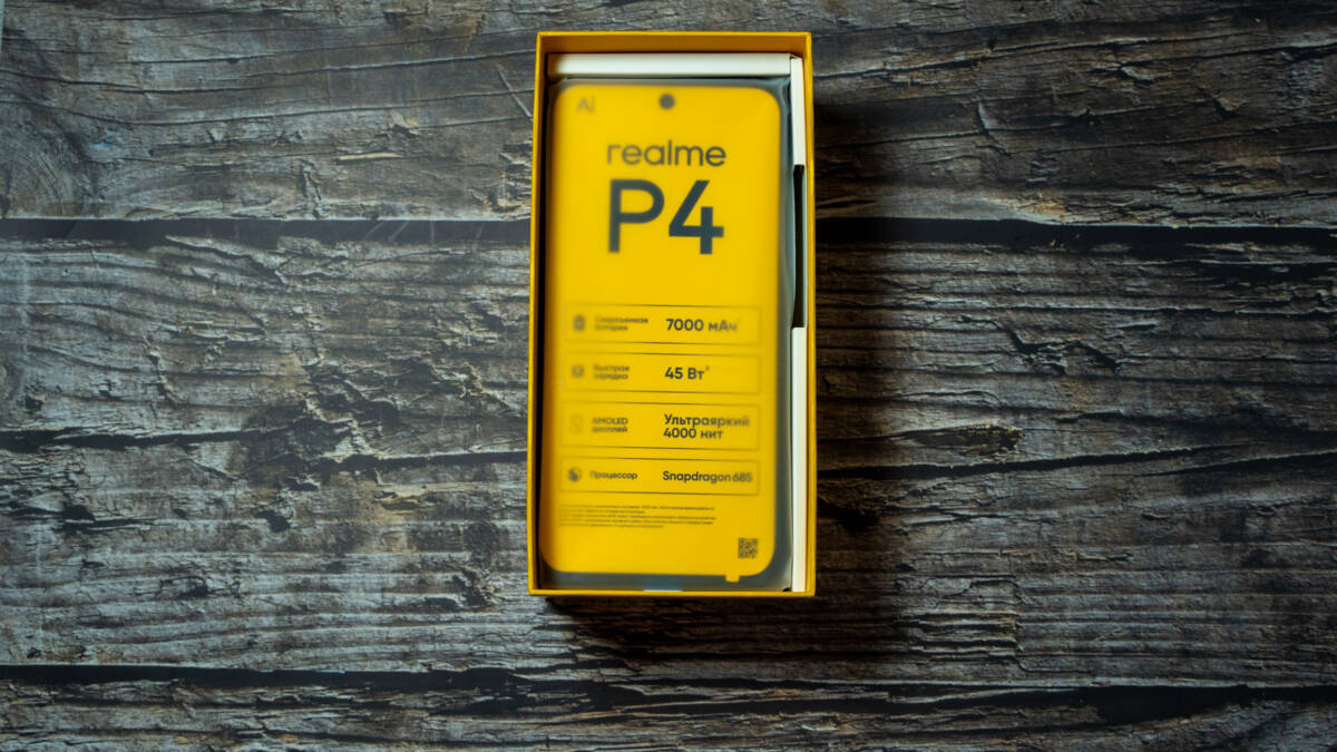 Коробка с смартфоном realme P4 на деревянном фоне