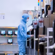 Работники в защитных костюмах у литографов с названиями устройств