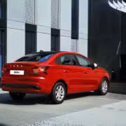 Красный седан Lada Iskra возле современного здания