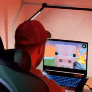 Человек играет в Minecraft на ноутбуке с RGB-клавиатурой