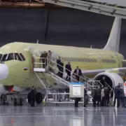 Самолет МС-21-210 на ремонтной площадке с высаживающимися пассажирами и техникой
