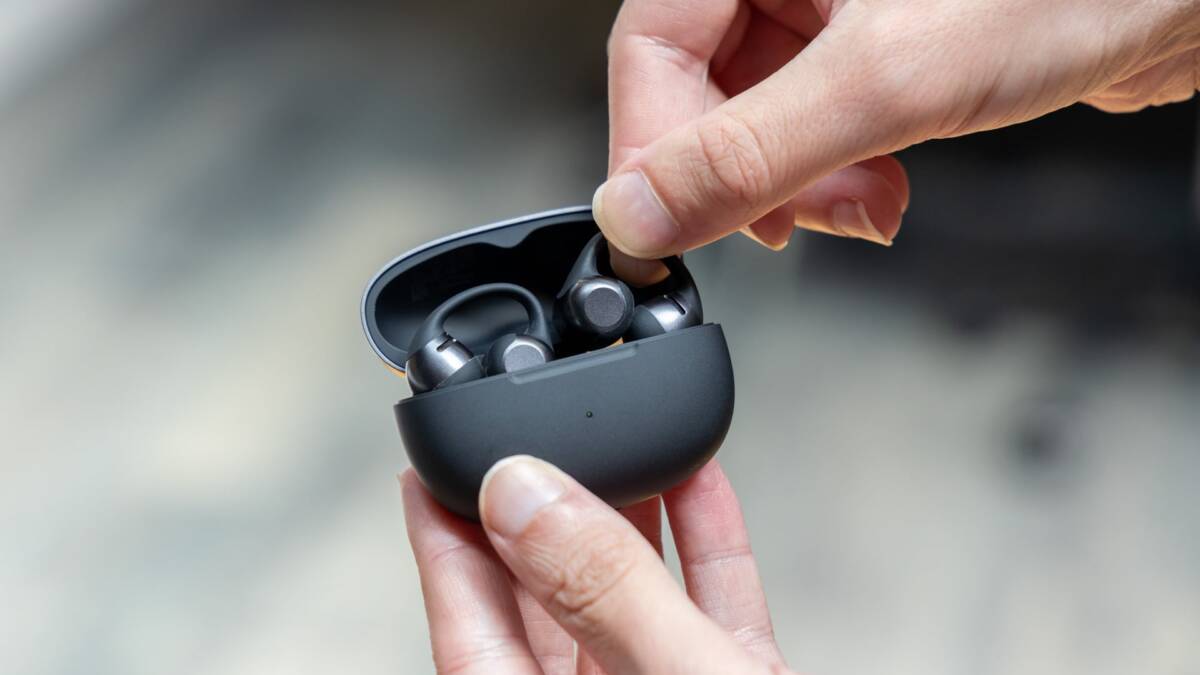 Человек держит наушники Shokz OpenDots 2 в руке