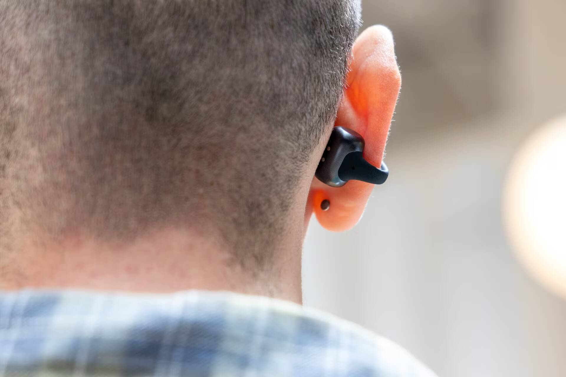 Человек в ухе использует наушники Shokz OpenDots 2