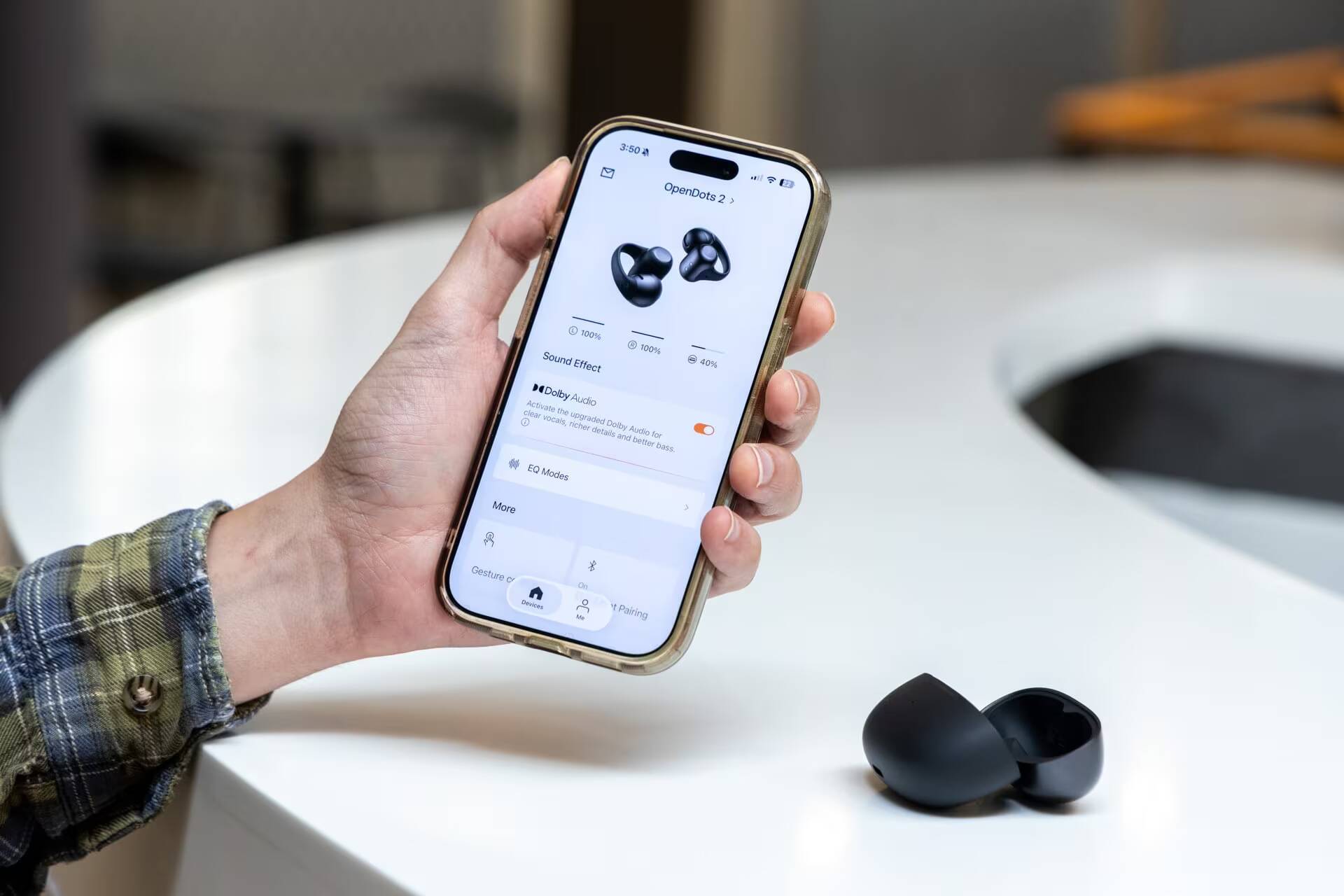 Человек держит смартфон с настройками Shokz OpenDots 2