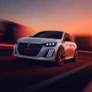Электрический Peugeot E-208 GTi на дороге при закате