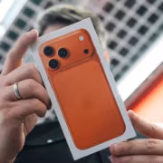 Человек держит коробку iPhone с оранжевым цветом