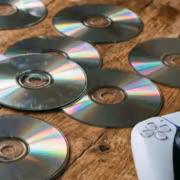 Диски для PlayStation и геймпад на деревянном столе
