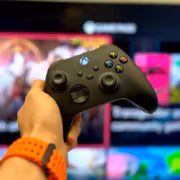 игрок с контроллером Xbox на фоне телевизора