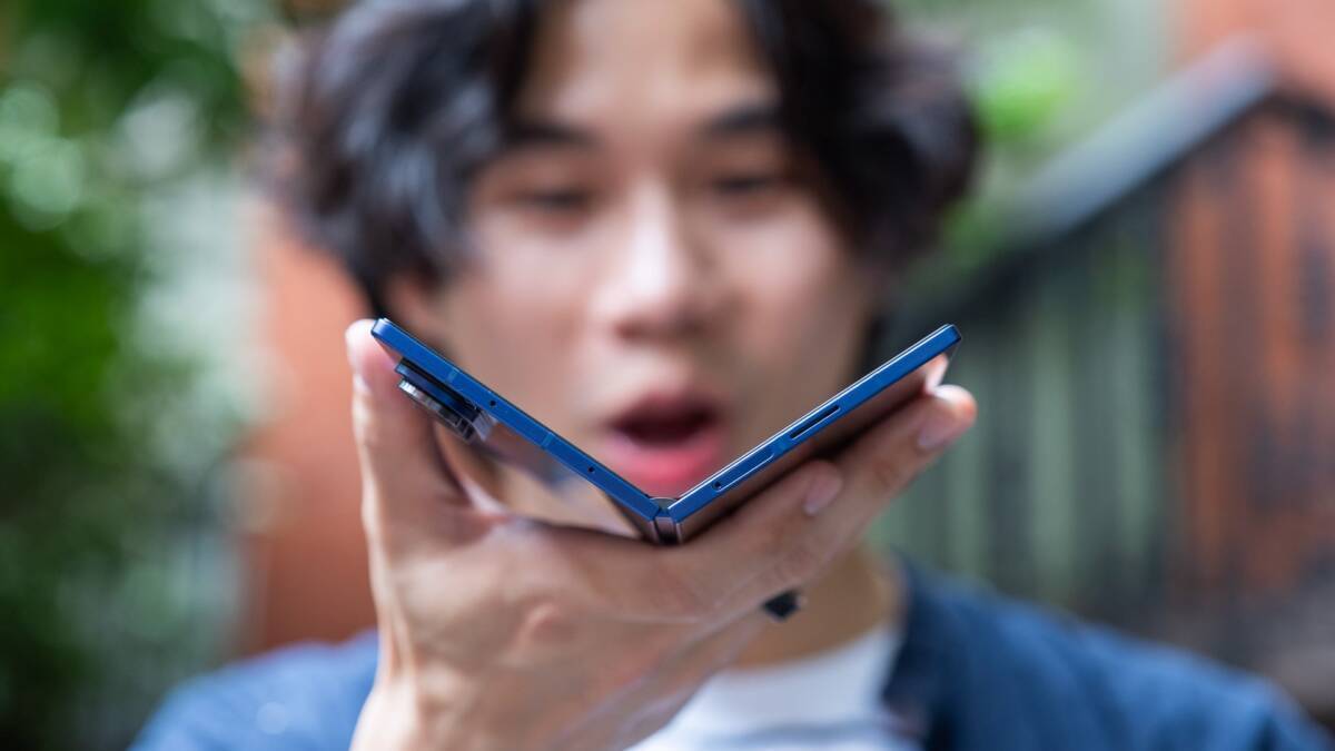 Молодой человек держит складной телефон Samsung Galaxy Fold 5
