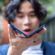 Молодой человек держит складной телефон Samsung Galaxy Fold 5