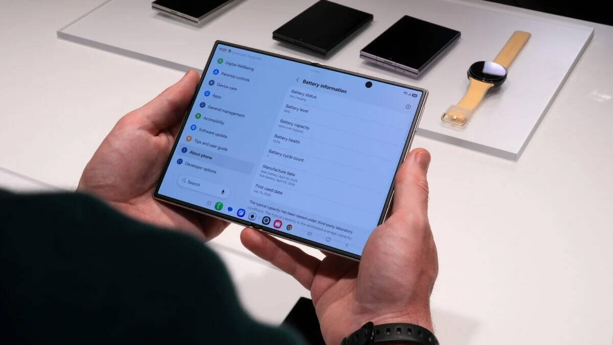 Человек держит складной смартфон Samsung Galaxy Fold показывающий настройки батареи