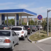Машины у заправочной станции с табличкой штрафы за очереди