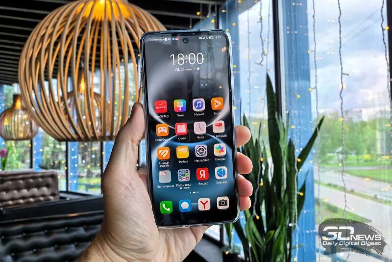 Рука держит смартфон Huawei nova Y74 внутри кафе