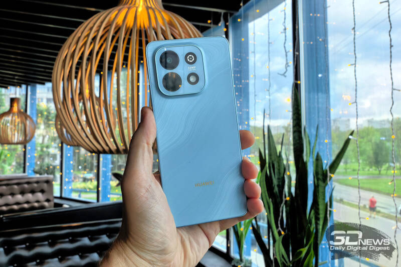 Рука держит голубой смартфон Huawei nova Y74 в помещении
