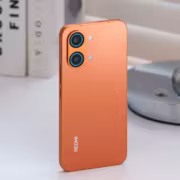 Красный смартфон Redmi Turbo 6 Max на белой поверхности