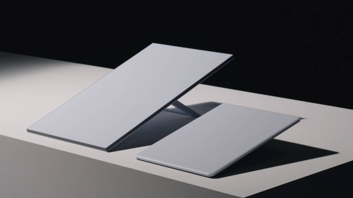 Два MacBook на белом столе, один черный другой белый, поднимающиеся крышки