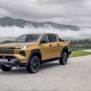 жёлтый пикап Toyota Hilux на дороге у озера