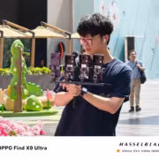 Молодой человек с очками и AirPods сортирует смартфоны OPPO Find X9 Ultra
