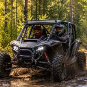 Багги Jeep с двумя водителями по грязной дороге в лесу