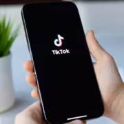 Мужчина держит iPhone с логотипом TikTok в руке