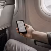 Xteink X4 Pro оказался крошечным ридером с кнопками и магнитом для смартфона 4 Человек держит устройство Xteink X4 Pro на борту самолёта