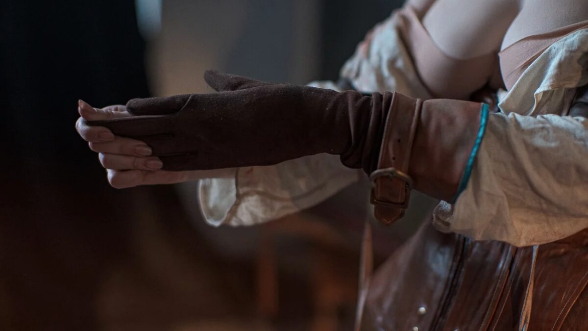 Руки в кожаных перчатках, в руках предмет из The Witcher 3