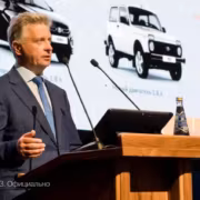 Микрофон на стойке, экран, бутылка воды, держащая лицо человека