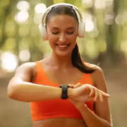 Девушка в наушниках проверяет время на умных часах Garmin Forerunner 745