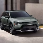 Мятный зеленый Kia Niro 2027 на улице с бетонной стеной