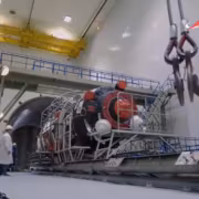 Космонавты Crew-13 у космического корабля Прогресс внутри цеха