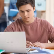 молодой человек за ноутбуком ASUS с книгами и учебными материалами