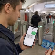 Мужчина держит телефон с SMS о пополнении Тройки в метро