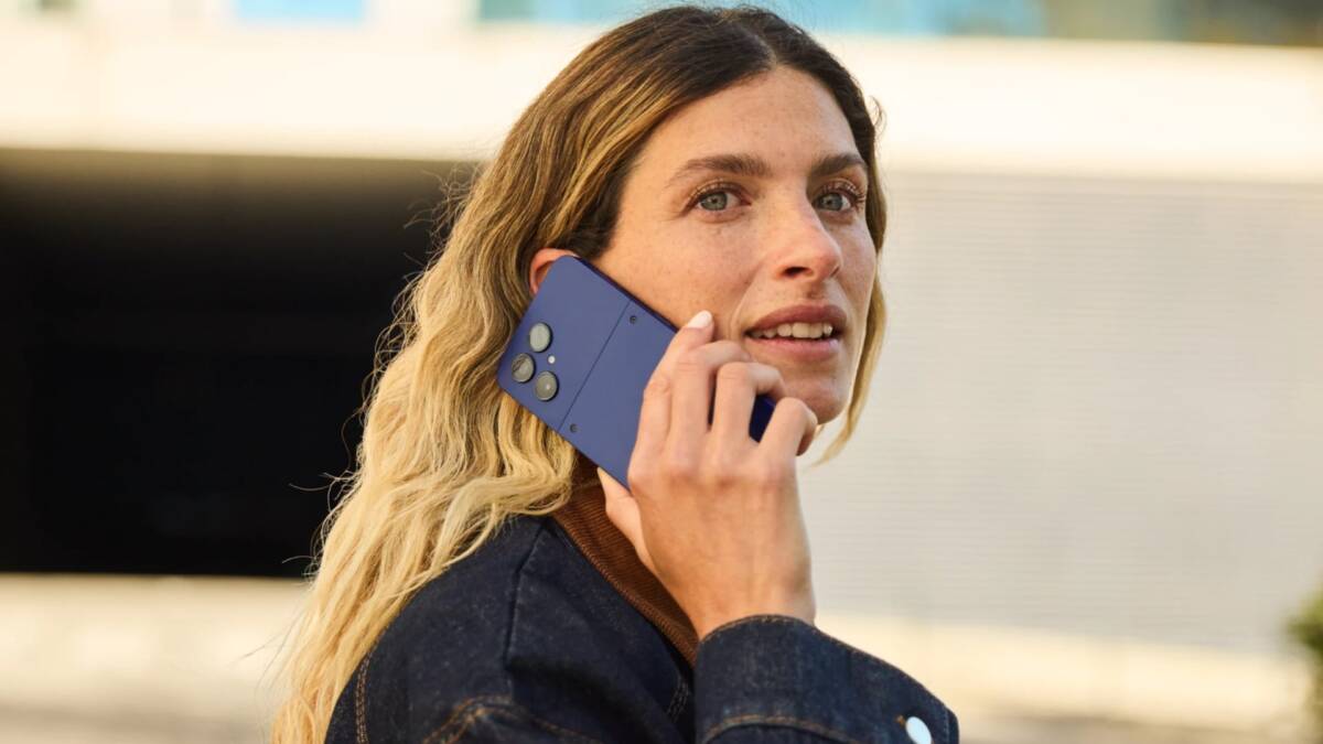 Женщина с длинными светлыми волосами держит смартфон Fairphone 6+ в руке