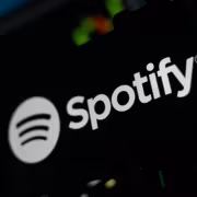 Логотип Spotify на темном фоне с частью устройства