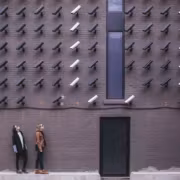 Камеры Flock на кирпичной стене, два человека идут